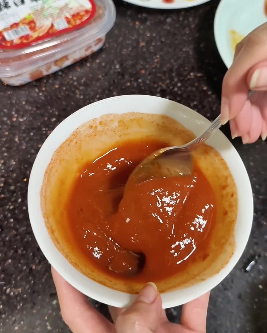 Zbliżenie na łyżkę mieszającą koreańską pastę sojową i chili z odrobiną wody do uzyskania gładkości.