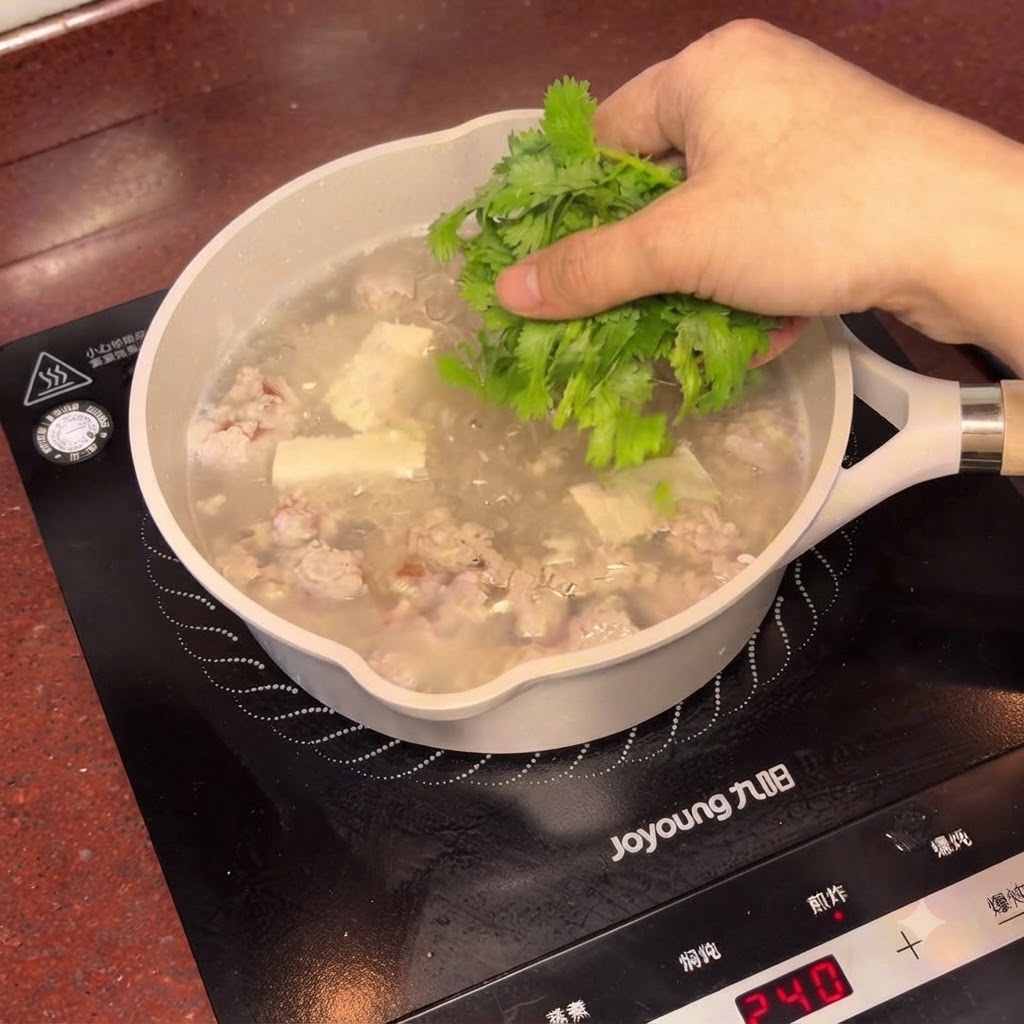 Świeżo posiekana kolendra posypywana po parującym garnku zupy z solonymi śliwkami i tofu.