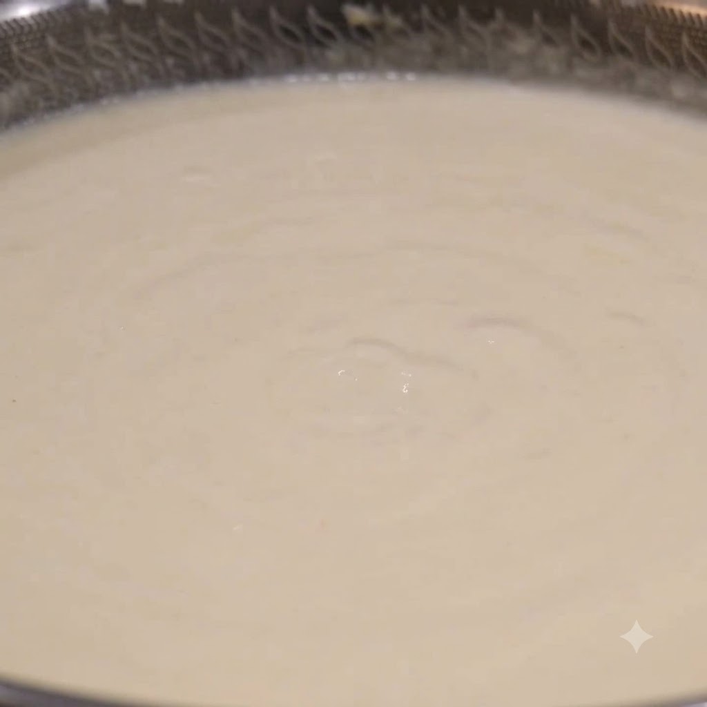 Chochla nabierająca kremowobiałą zupę chowder z bulgoczącego woka.
