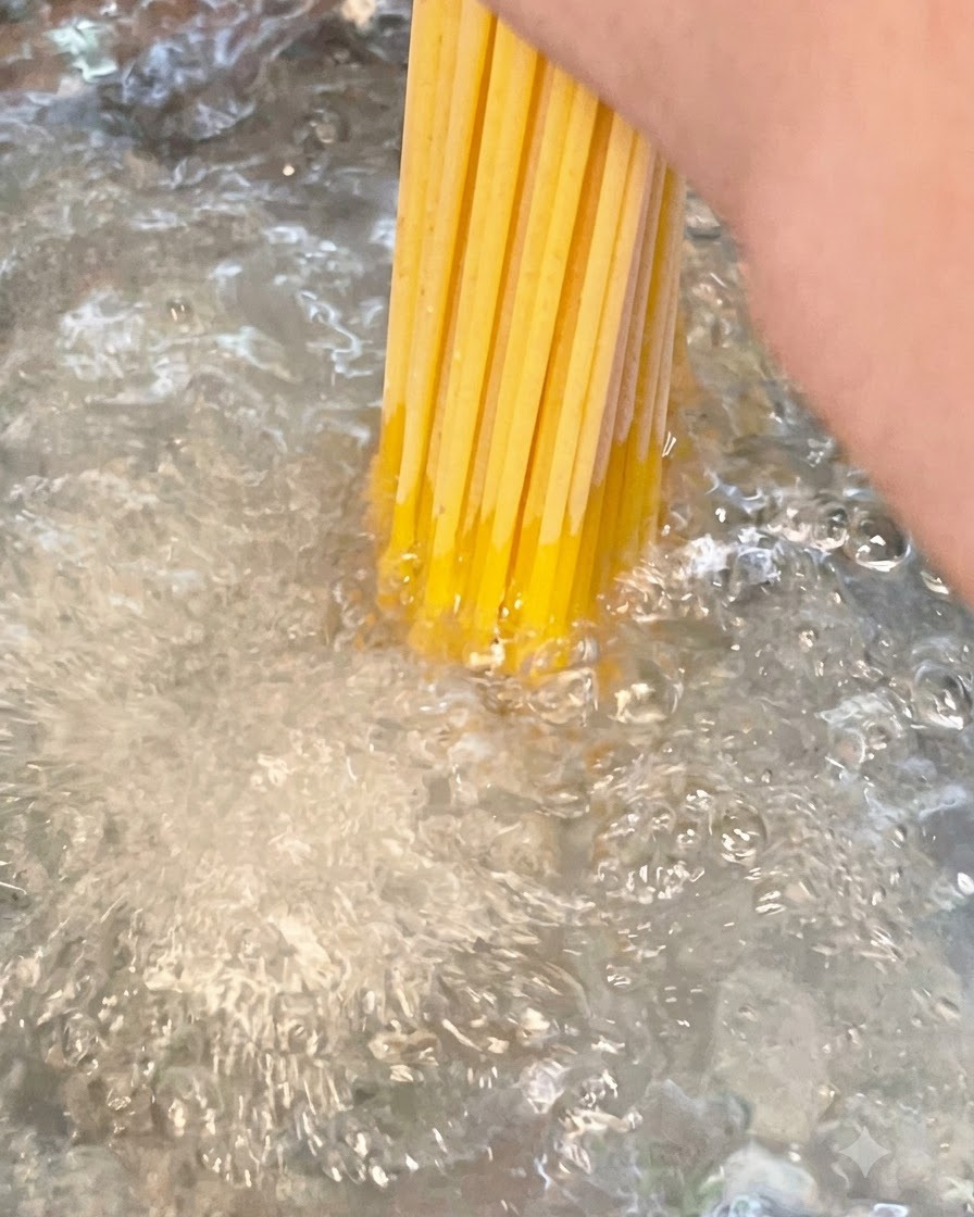 Wiązka suchego długiego spaghetti zanurzana w garnku z gotującą się soloną wodą.