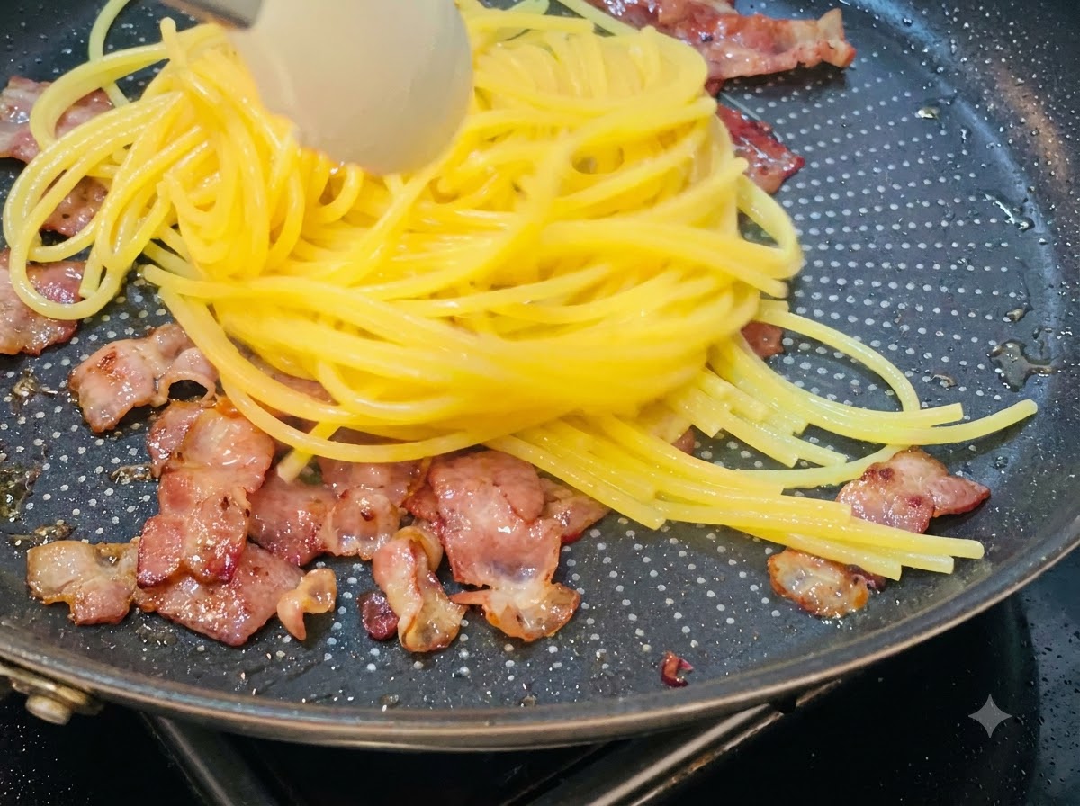 Ugotowane spaghetti wyciąganie i przekładane na patelnię zawierającą podsmażone kawałki boczku.