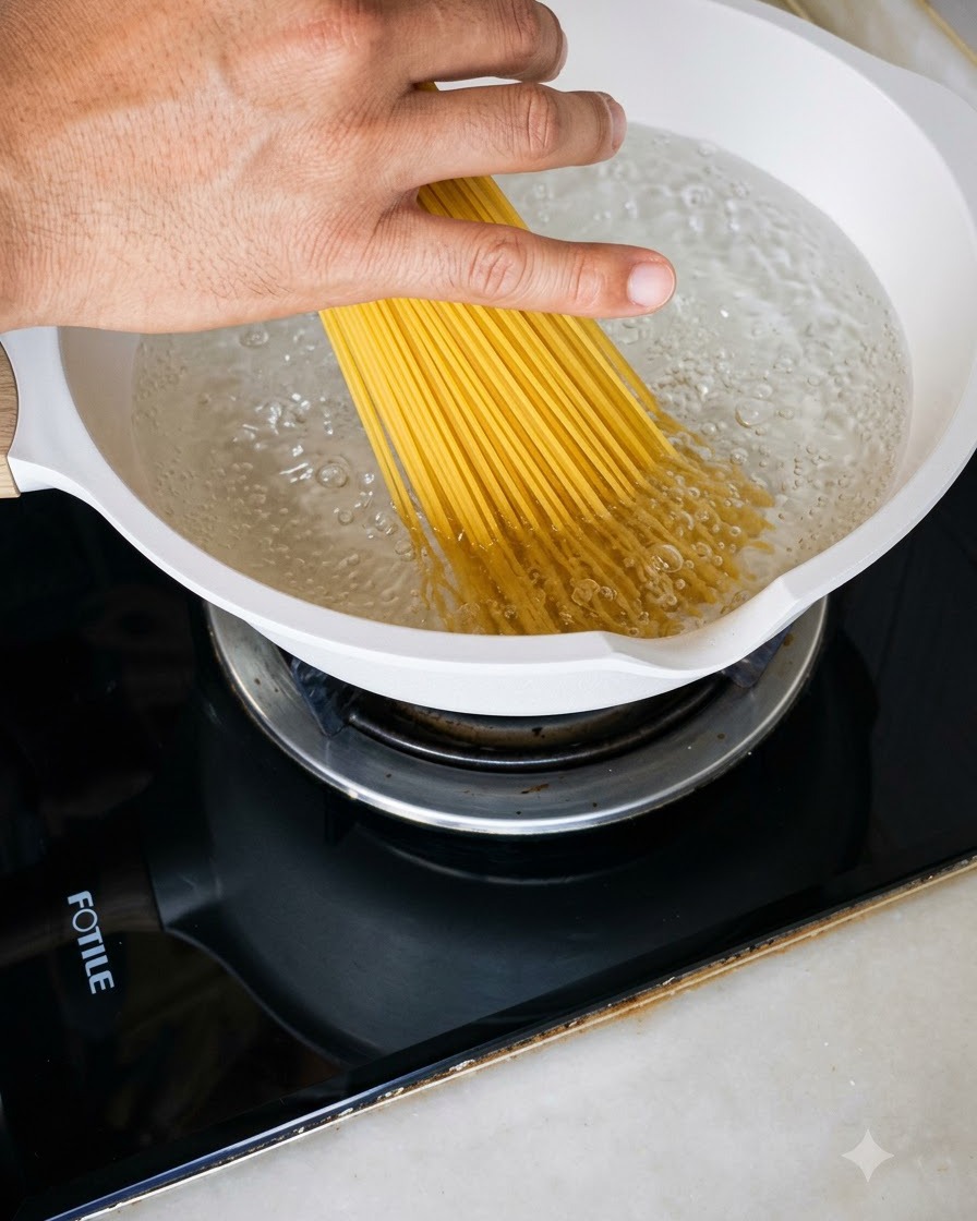 Garść suchego makaronu spaghetti wrzucana do białego garnka wypełnionego bulgoczącą wrzącą wodą.