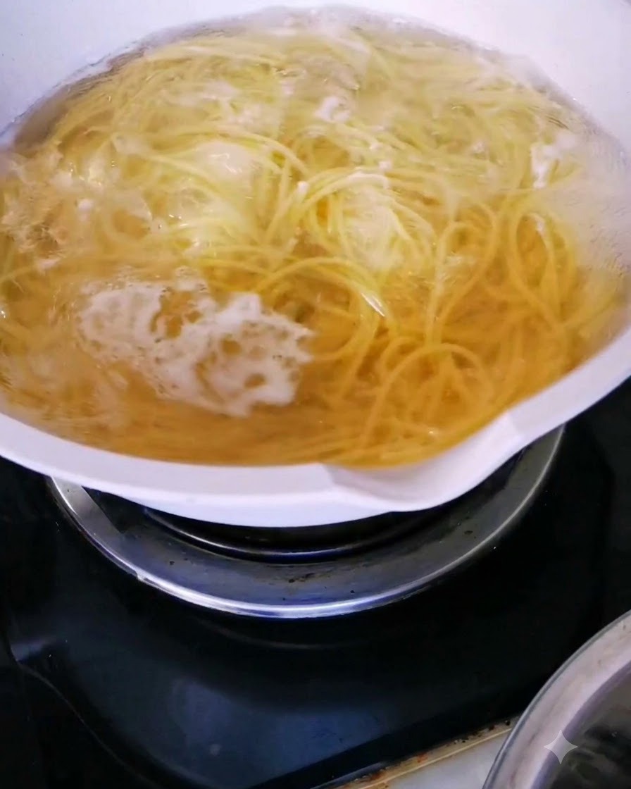 Nodle spaghetti gotujące się aktywnie w garnku z gorącą wodą.