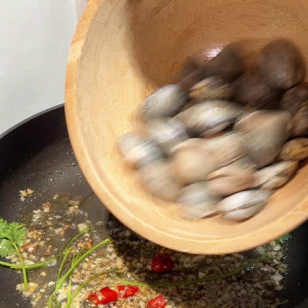 Małże przesypywane z drewnianej miski na patelnię ze smażącym się czosnkiem i chili.