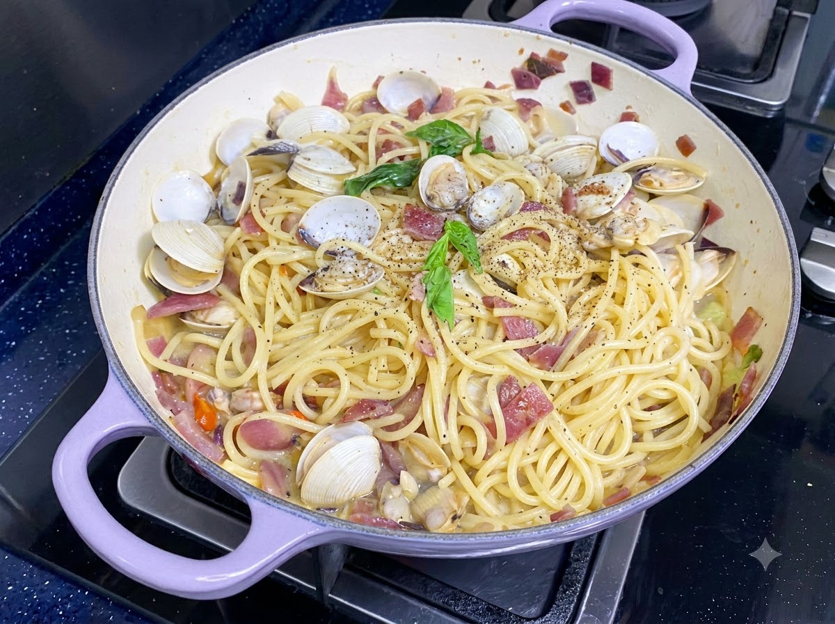 Świeże zielone liście bazylii ułożone na wierzchu gotowego spaghetti z małżami.