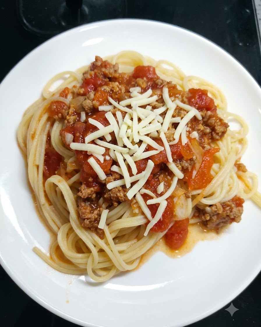 Tarta mozzarella posypana na spaghetti pokryte sosem pomidorowym na białym talerzu.