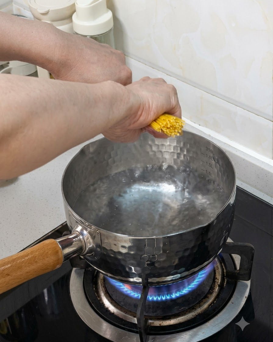 Pęczek makaronu spaghetti wrzucany do garnka z wrzącą wodą na kuchence gazowej.
