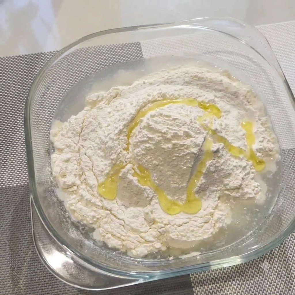 Oliwa z oliwek polewana na mieszankę mąki i wody w szklanej misce.