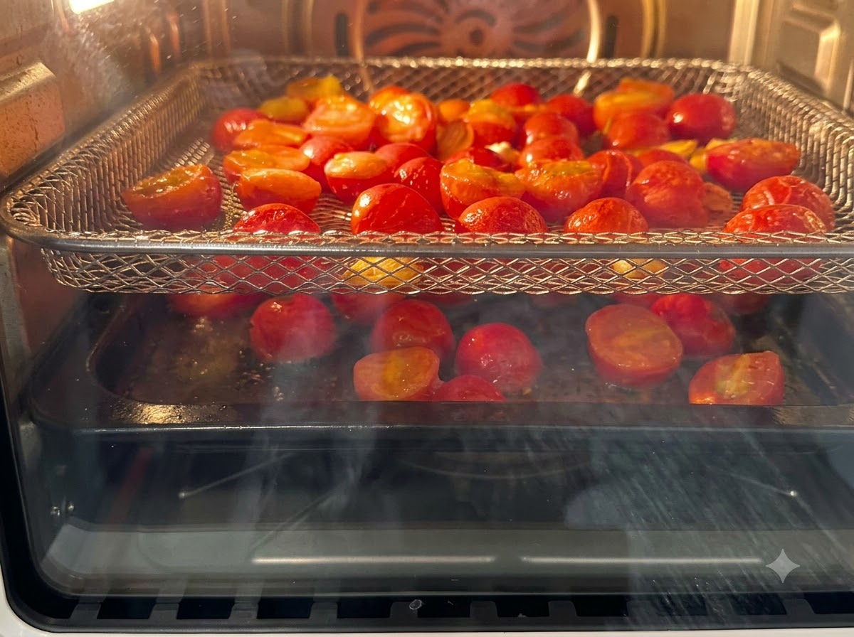 Przekrojone na pół pomidorki koktajlowe ułożone na ruszcie frytkownicy beztłuszczowej (air fryer) podczas pieczenia.