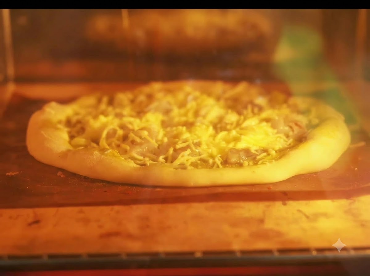Pizza piekąca się na blasze w rozgrzanym piekarniku z żarzącymi się grzałkami.