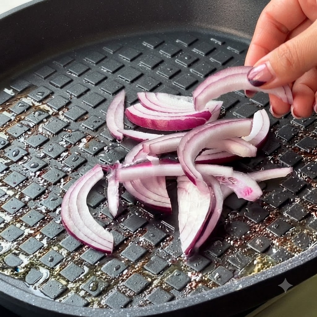 Pokrojona czerwona cebula i kimchi dodawane są na patelnię.