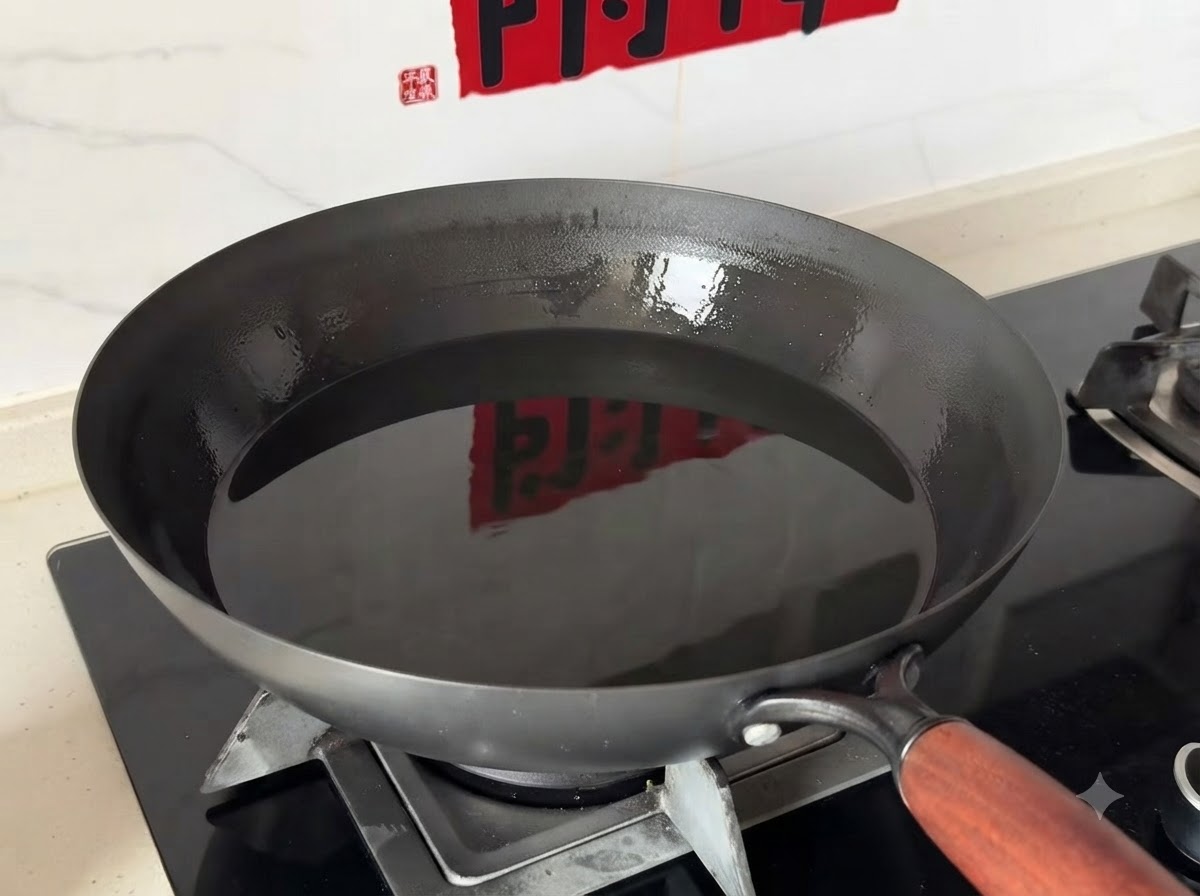 Głęboki wok wypełniony czystym olejem stojący na palniku kuchenki gazowej.