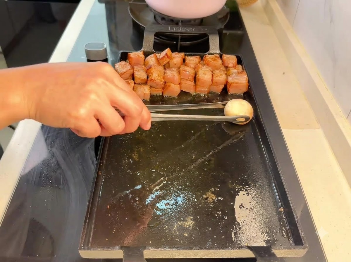 Pieczarka układana szczypcami na grillu obok grillowanych kawałków mięsa.