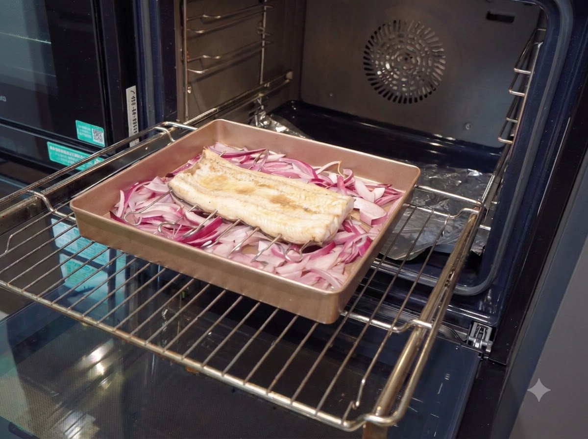 Pędzel cukierniczy nakładający gęsty, ciemnobrązowy sos na częściowo upieczony filet z węgorza w naczyniu do pieczenia.