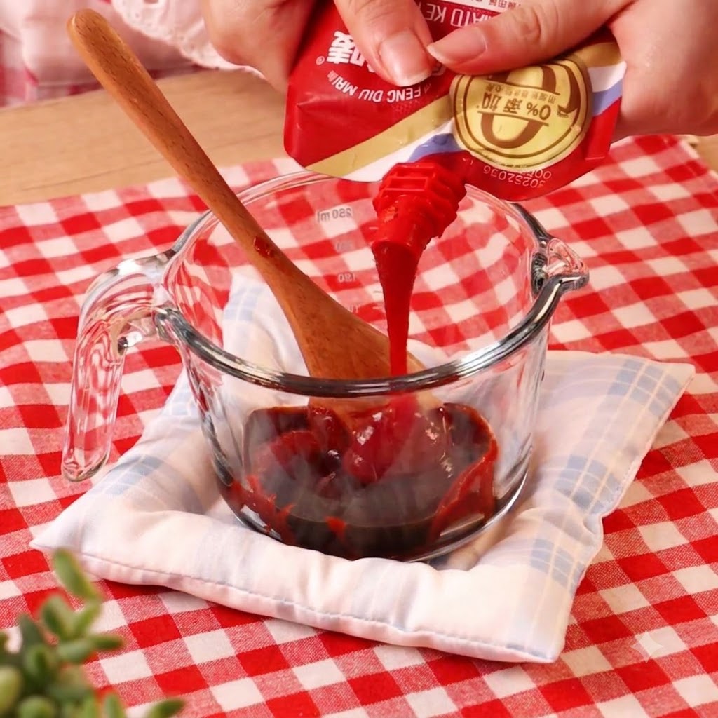 Pasta chili wlewana z saszetki do szklanej miarki zawierającej inne płyny.