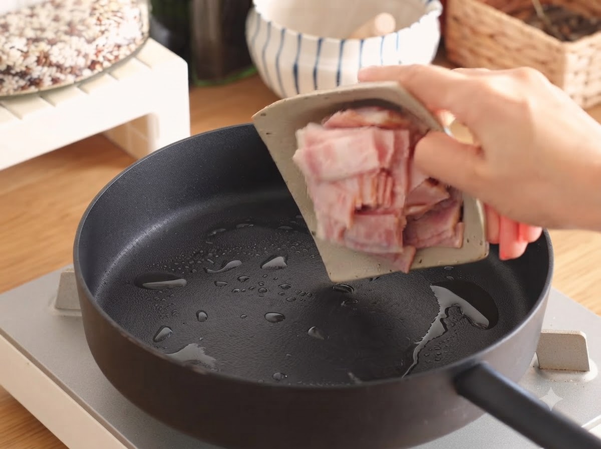 Paski bekonu skwierczące na patelni z niewielką ilością oleju.