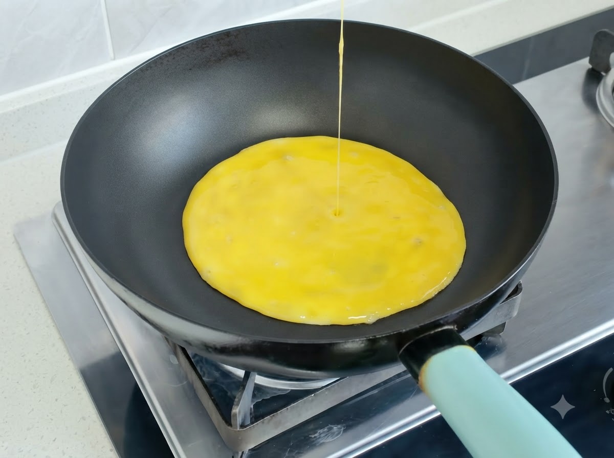 Mieszanina roztrzepanych jaj wlewana na rozgrzaną patelnię w celu utworzenia omletu.