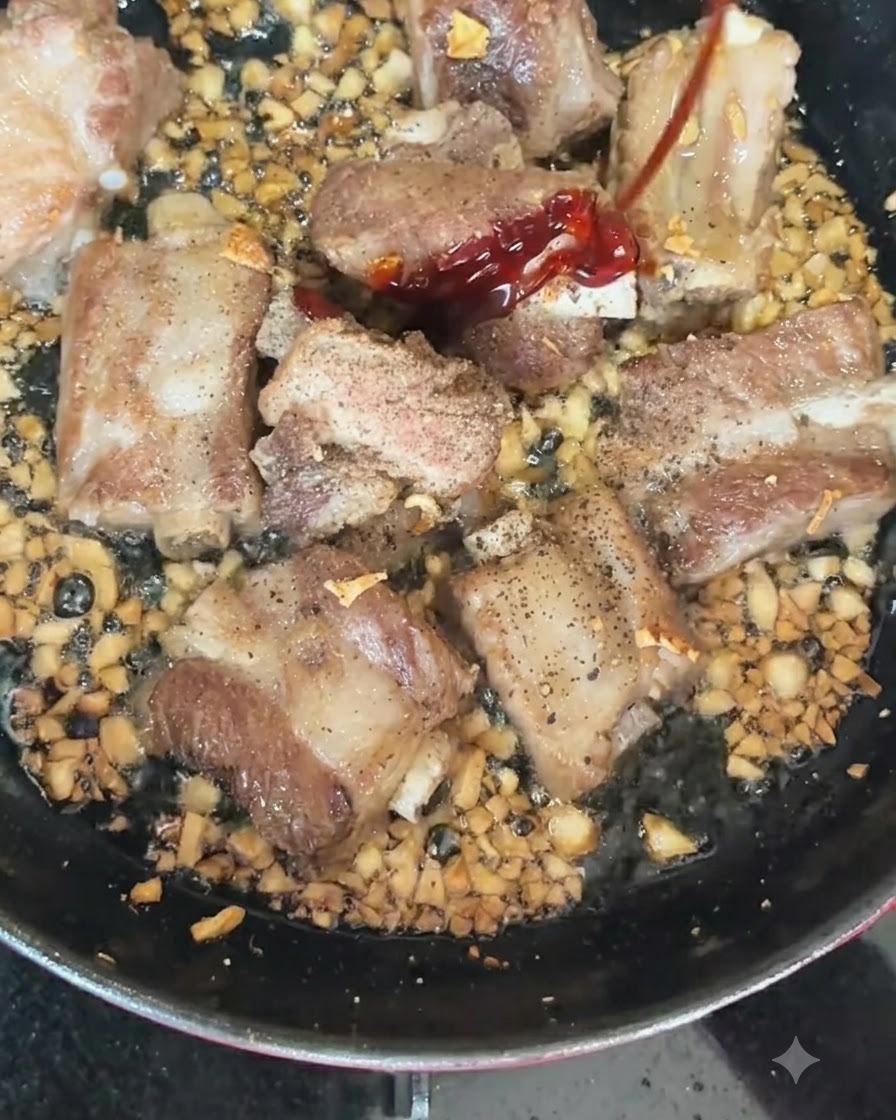 Czerwone i zielone chili dodawane do gorącej patelni ze skwierczącymi żeberkami i posiekanym czosnkiem.