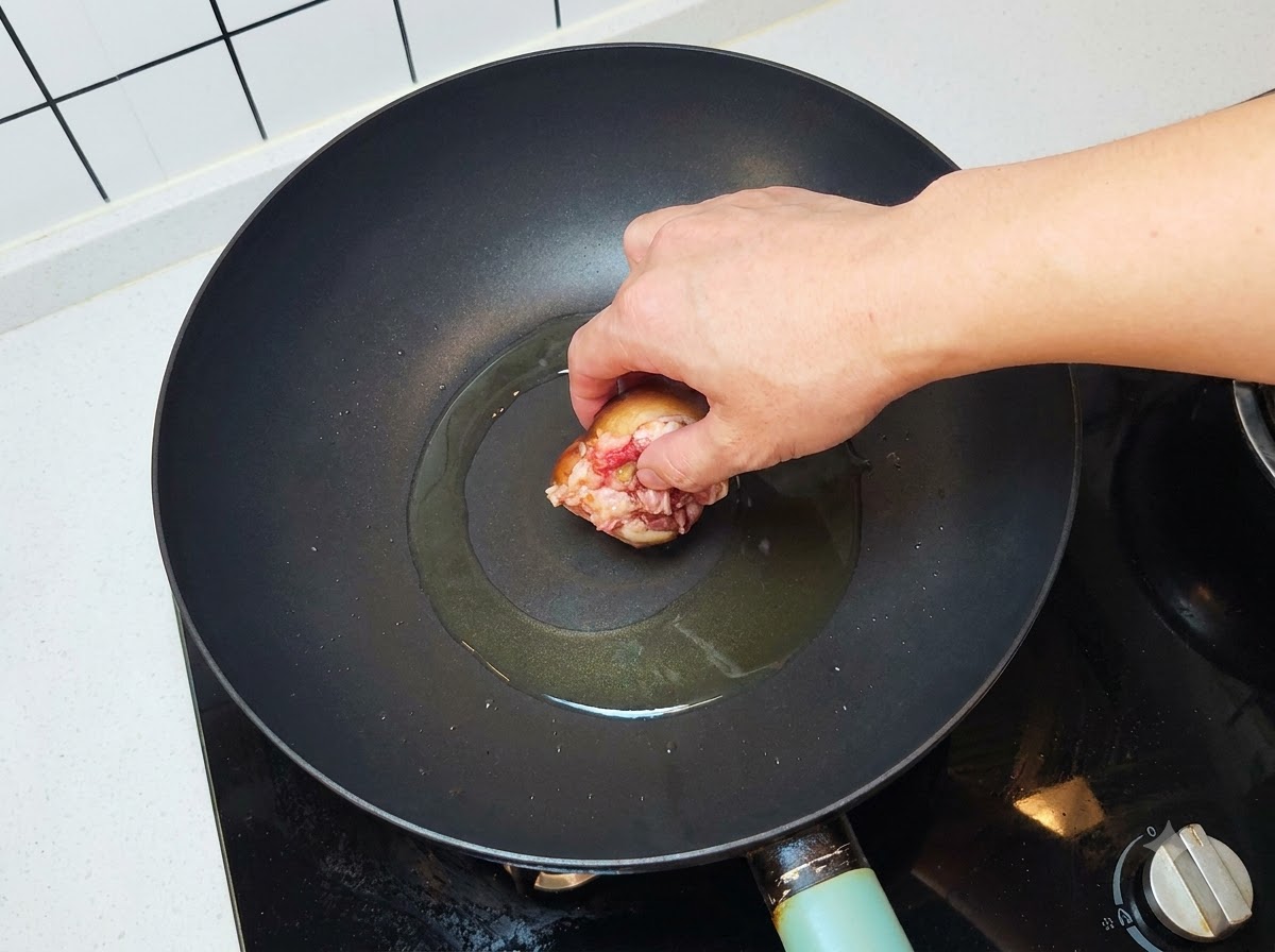 Faszerowany grzyb wkładany mięsem do dołu na gorący, naoliwiony wok.