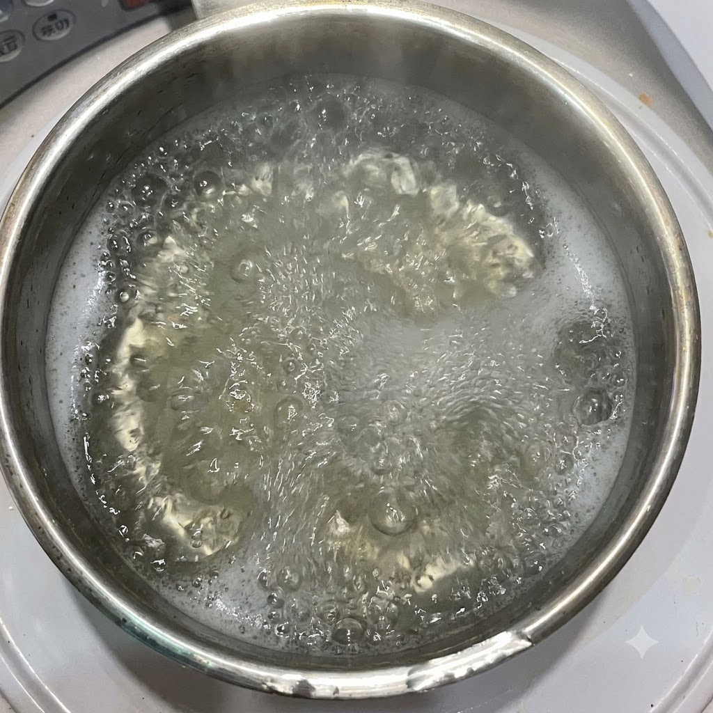 Oliwa z oliwek wlewana do garnka z wrzącą wodą i makaronem penne.