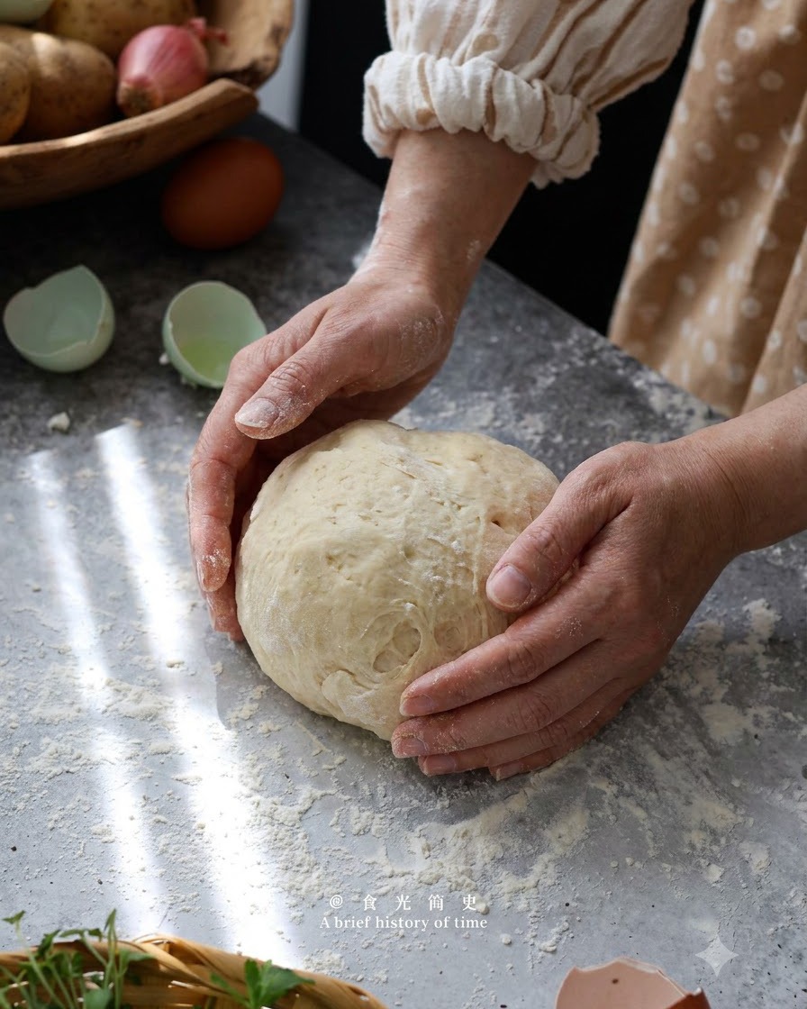 Ręce delikatnie formujące i wyrabiające ciasto gnocchi w kulę na oprószonej mąką powierzchni.