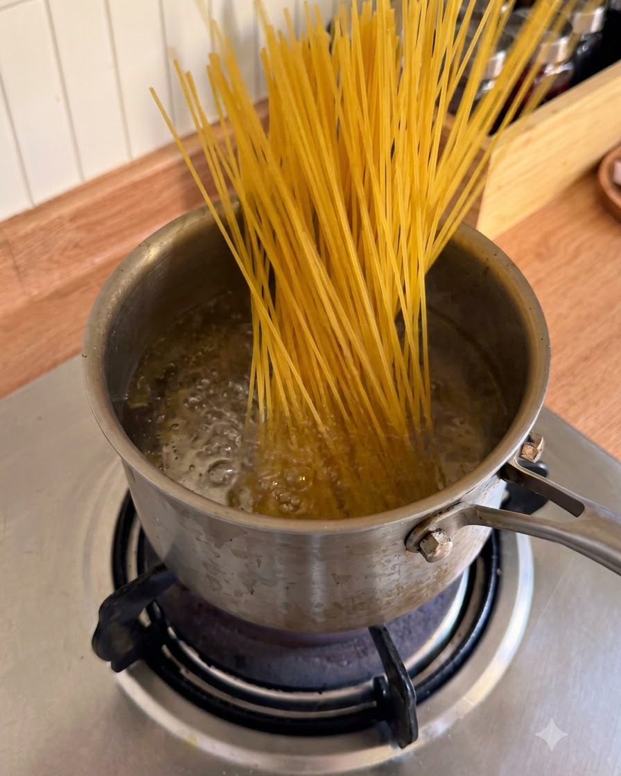 Suche nitki spaghetti wkładane do garnka z bulgoczącą, wrzącą wodą.