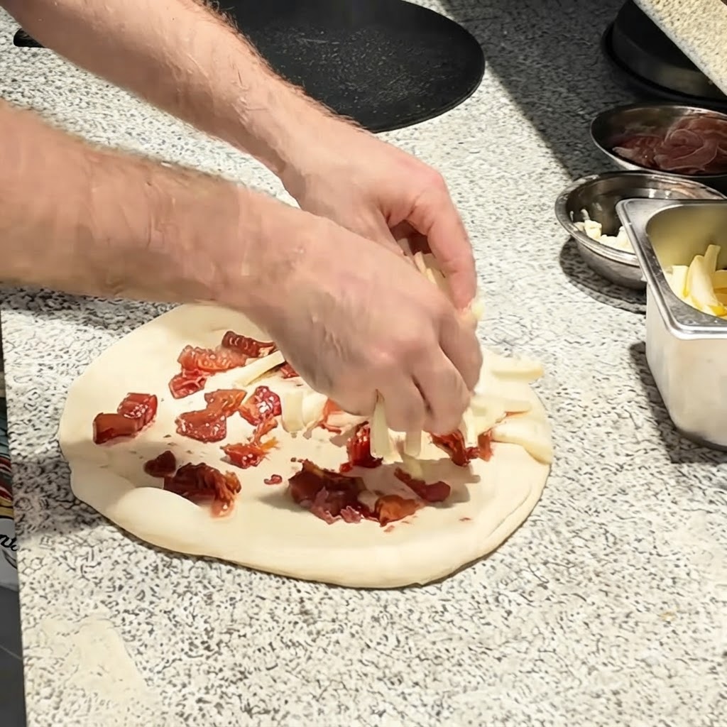 Kawałki sera mozzarella posypywane na ciasto do pizzy.