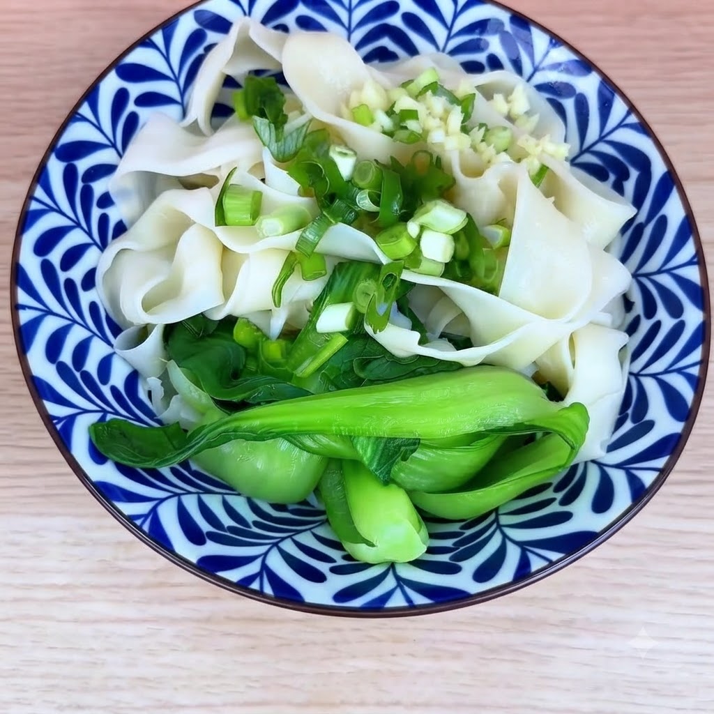 Miska ugotowanego makaronu i bok choy posypana posiekaną zieloną cebulką i posiekanym czosnkiem.