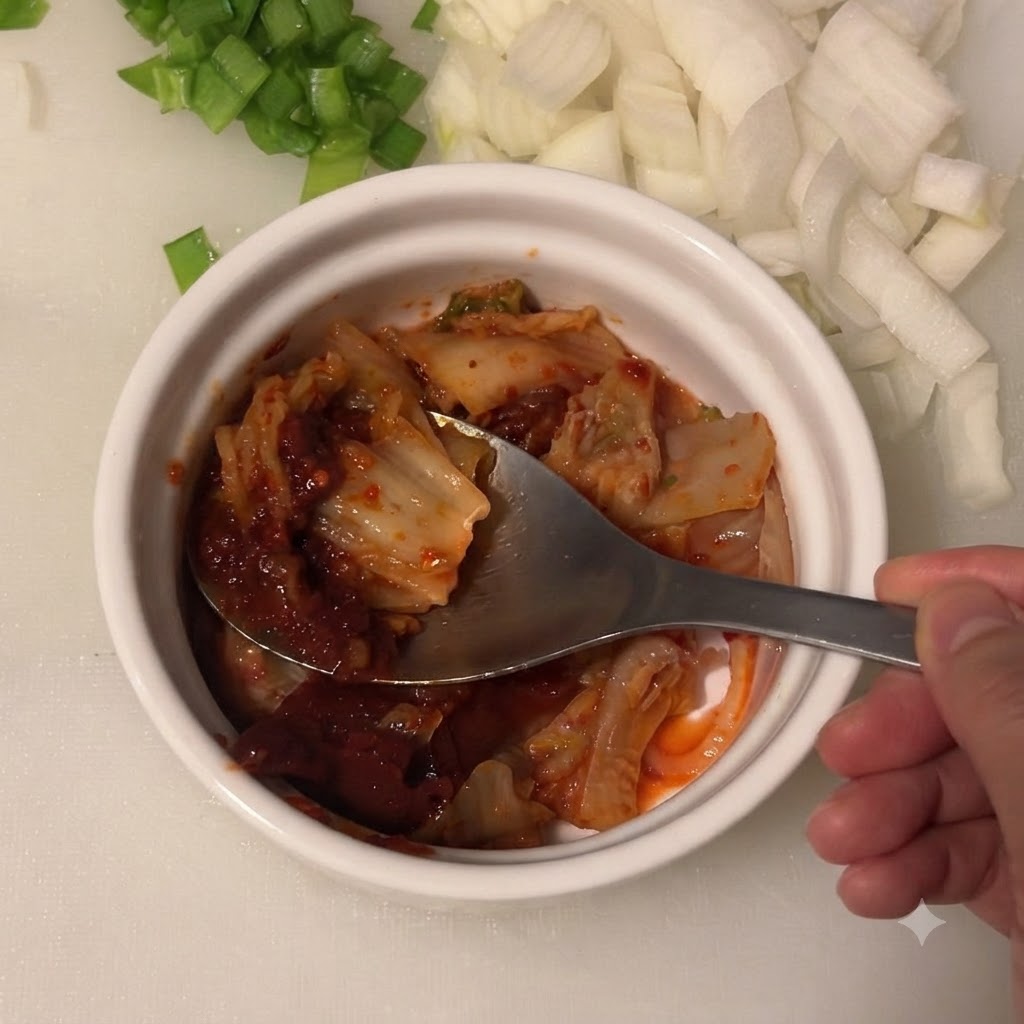 Jasny sos sojowy wlewany do miski zawierającej kimchi i koreańską pastę chili.
