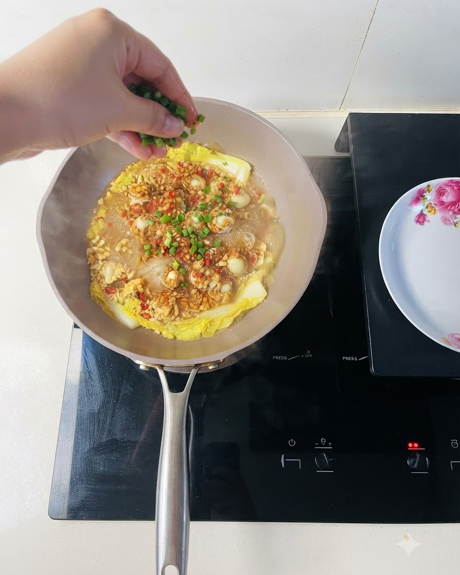 Świeżo posiekana zielona cebulka posypana na ugotowane małże i makaron vermicelli.
