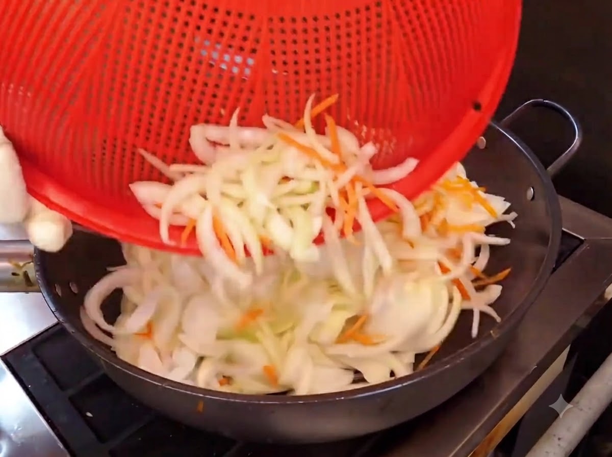 Paski cebuli i marchewki wsypywane z czerwonego koszyka na gorący wok do smażenia.