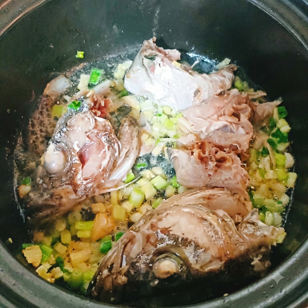 Kawałki i głowa mintaja smażące się w garnku z posiekanymi aromatami.