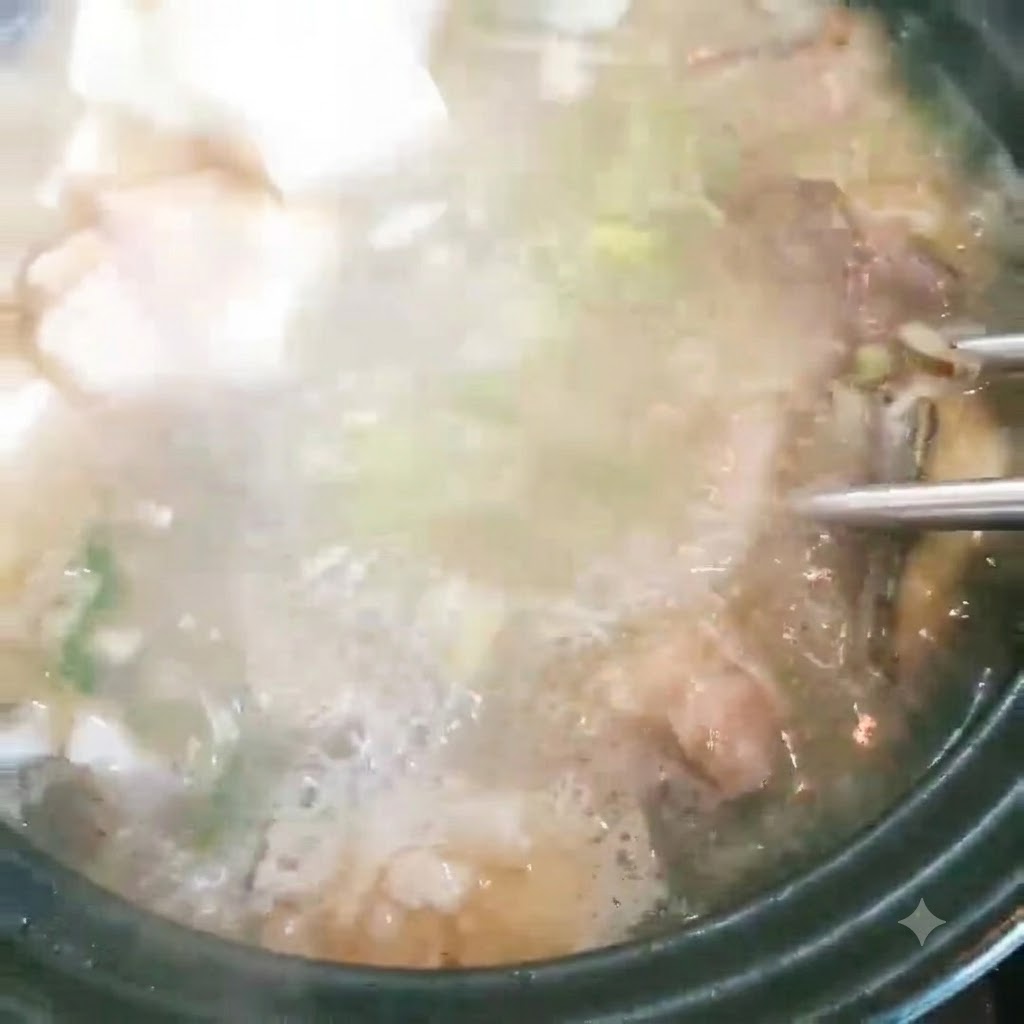 Kostki tofu wrzucane do garnka z bulgoczącą zupą rybną i zieloną cebulką.