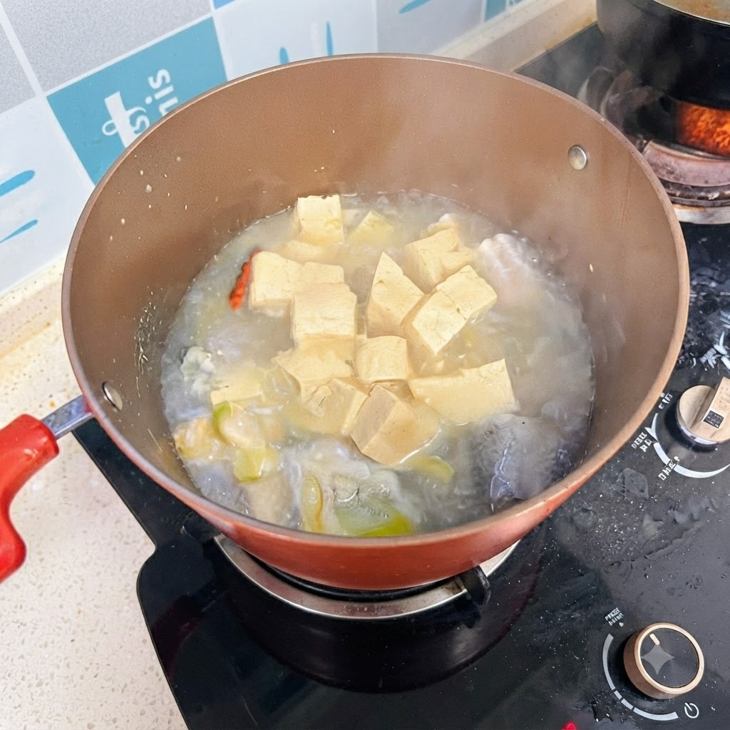 Gotująca się zupa rybna z tofu z wyrazistym, mlecznobiałym wywarem.