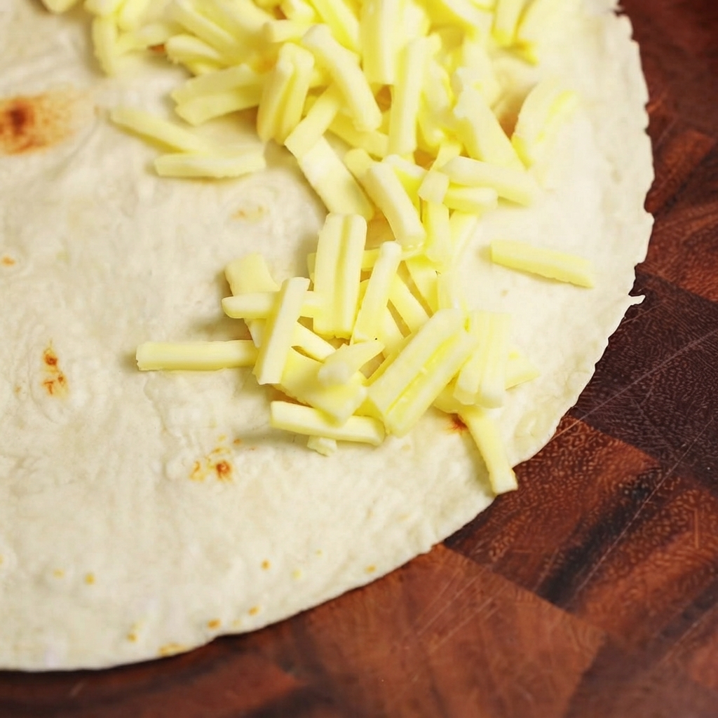 Ugotowany farsz mięsny i ser mozzarella ułożone na jednej połowie płaskiej pszennej tortilli.
