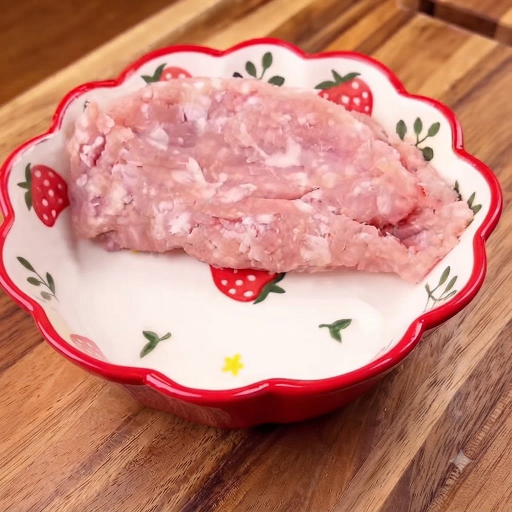 Mielona wieprzowina w ozdobnej misce z posiekaną zieloną cebulką na wierzchu.