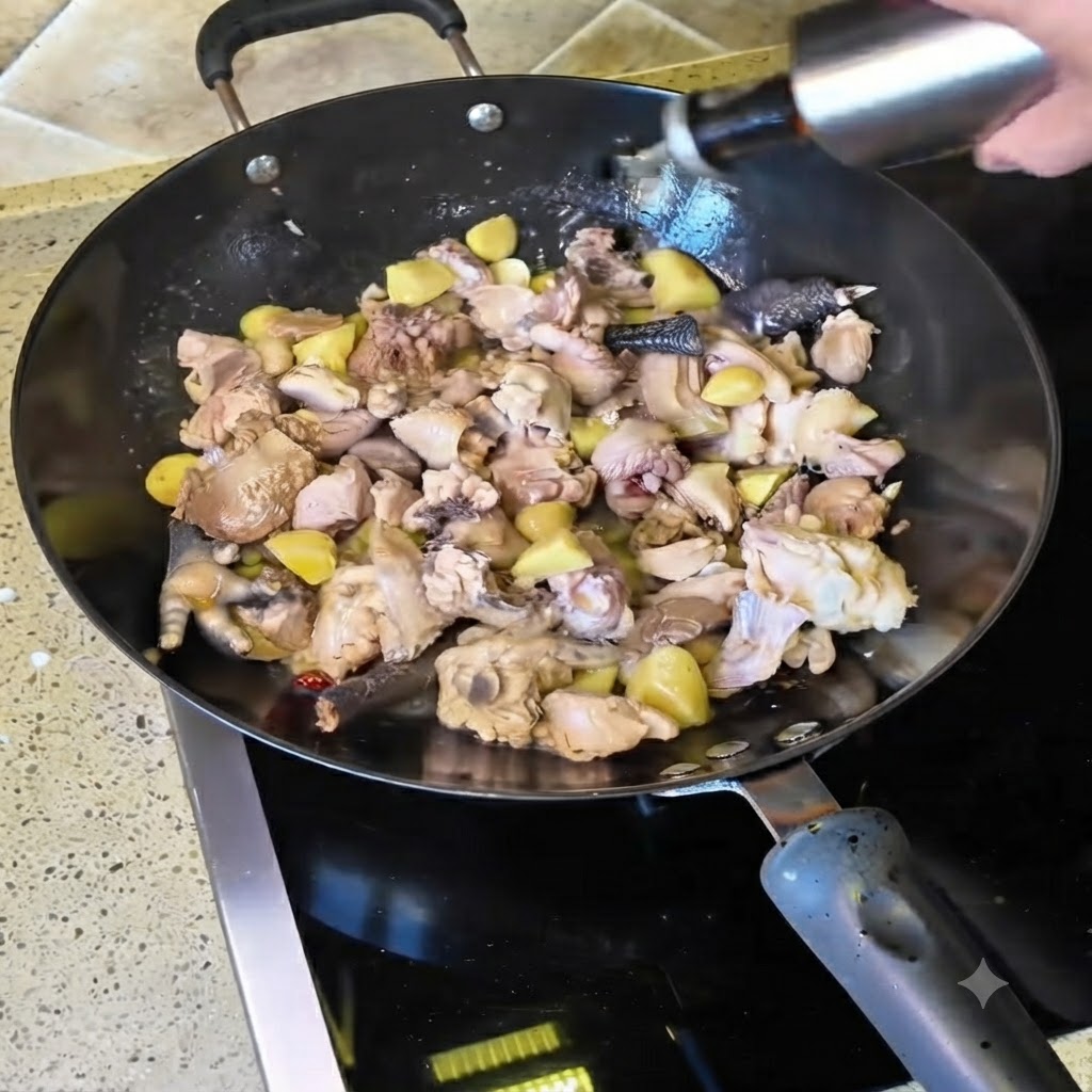 Żółte wino wlewane z butelki do woka wypełnionego smażonymi kawałkami kurczaka.