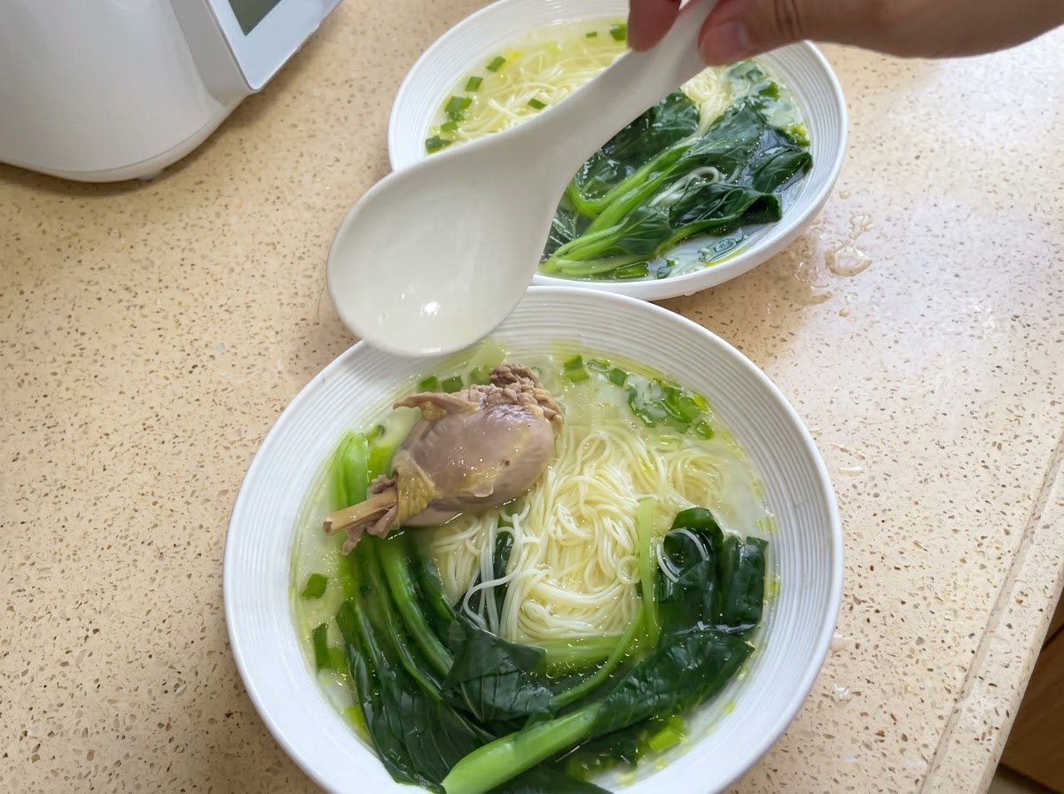 Miska makaronu udekorowana kawałkiem kurczaka i ugotowaną kapustą bok choy.