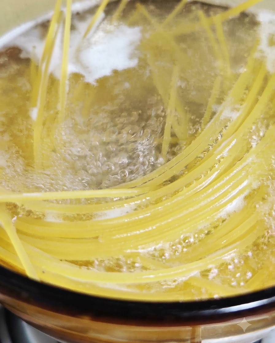 Kluski spaghetti gotujące się i bulgoczące w garnku z gotującą się osoloną wodą.