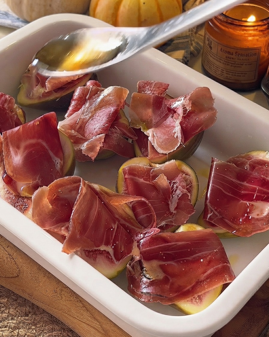 Miód skrapiany z łyżki na przygotowane figi i prosciutto w naczyniu do zapiekania.