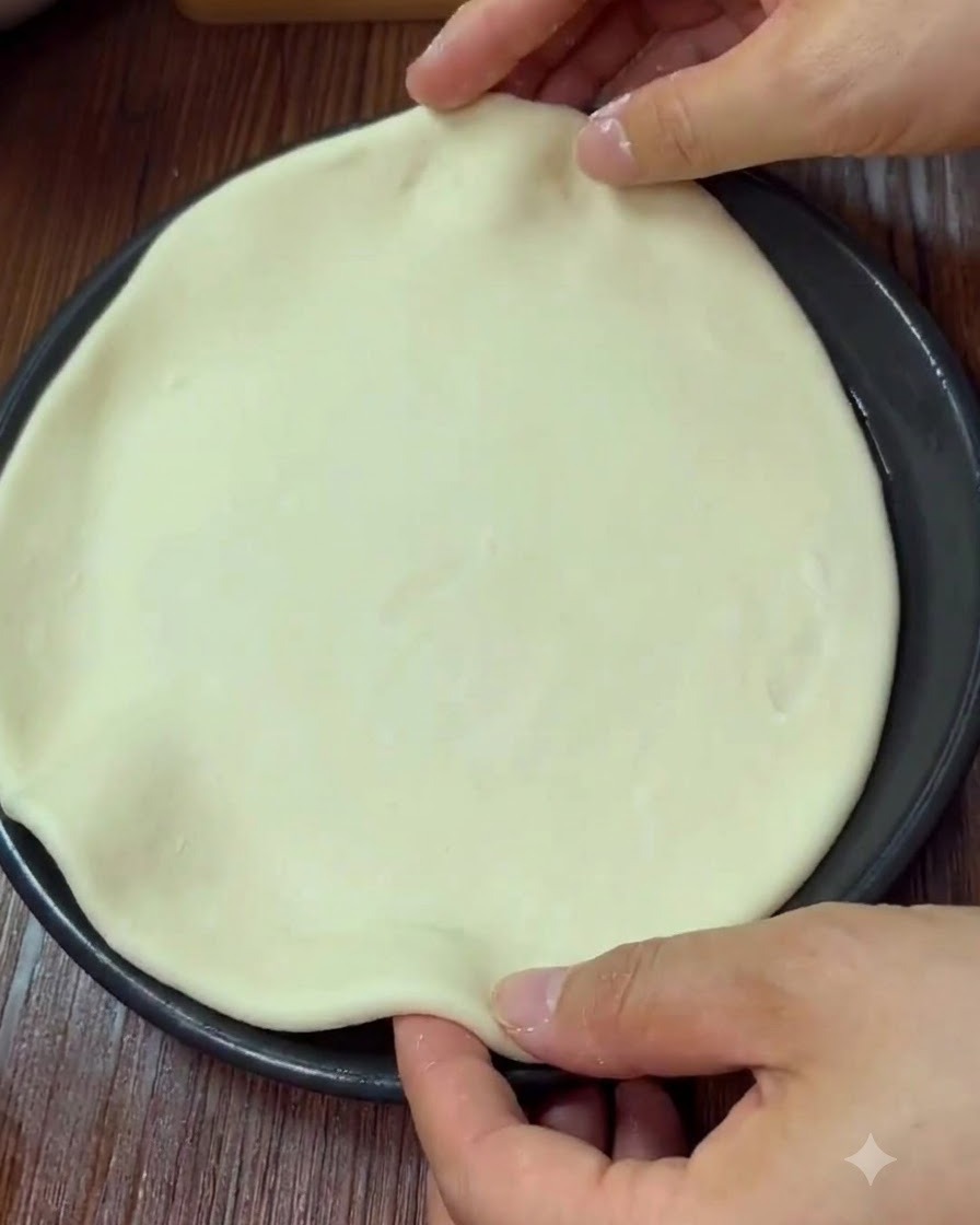 Ręce kształtujące i ściskające krawędź okrągłego ciasta do pizzy w formie do pieczenia.
