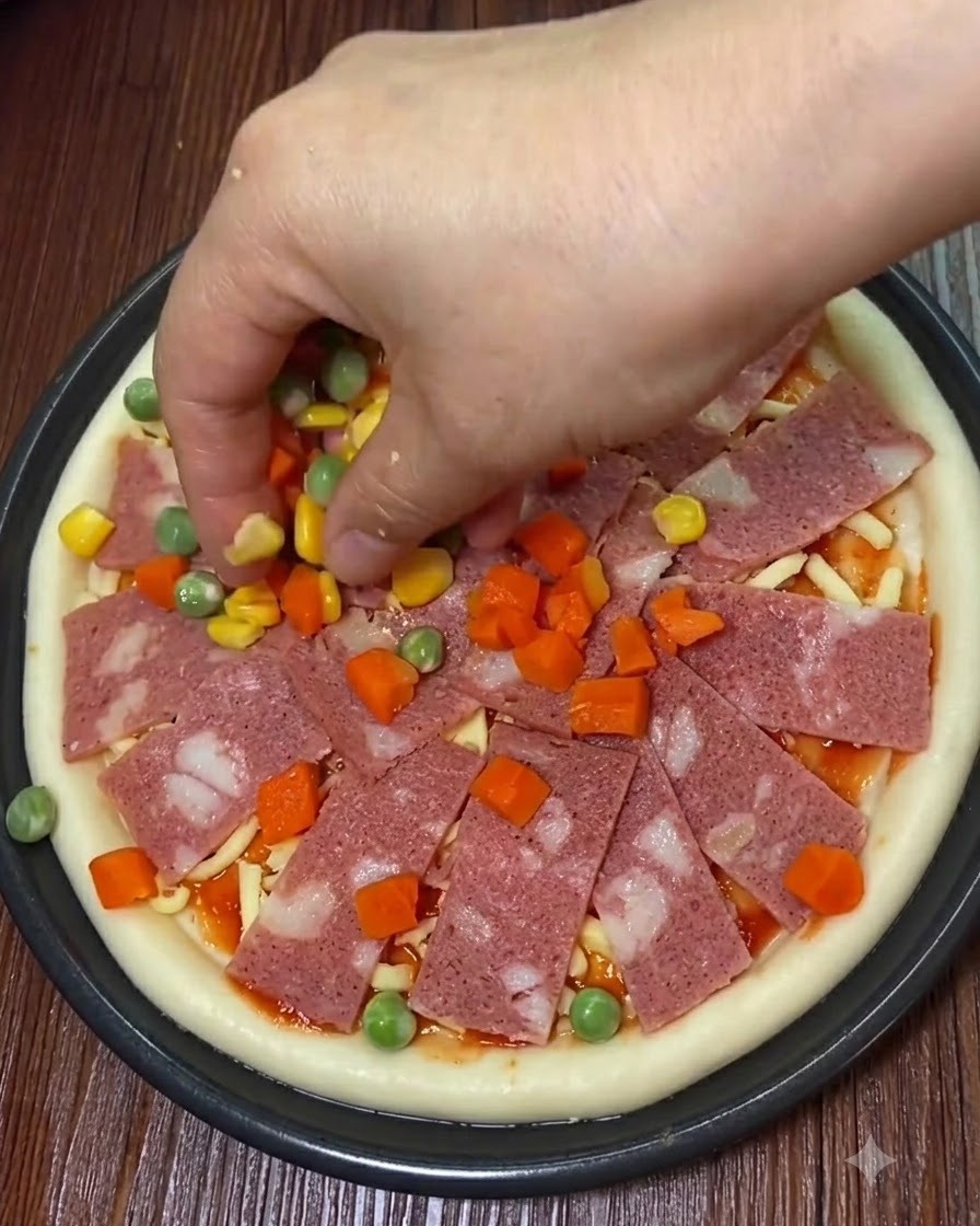 Plasterki boczku, słodka kukurydza i pokrojone warzywa umieszczane na pizzy.