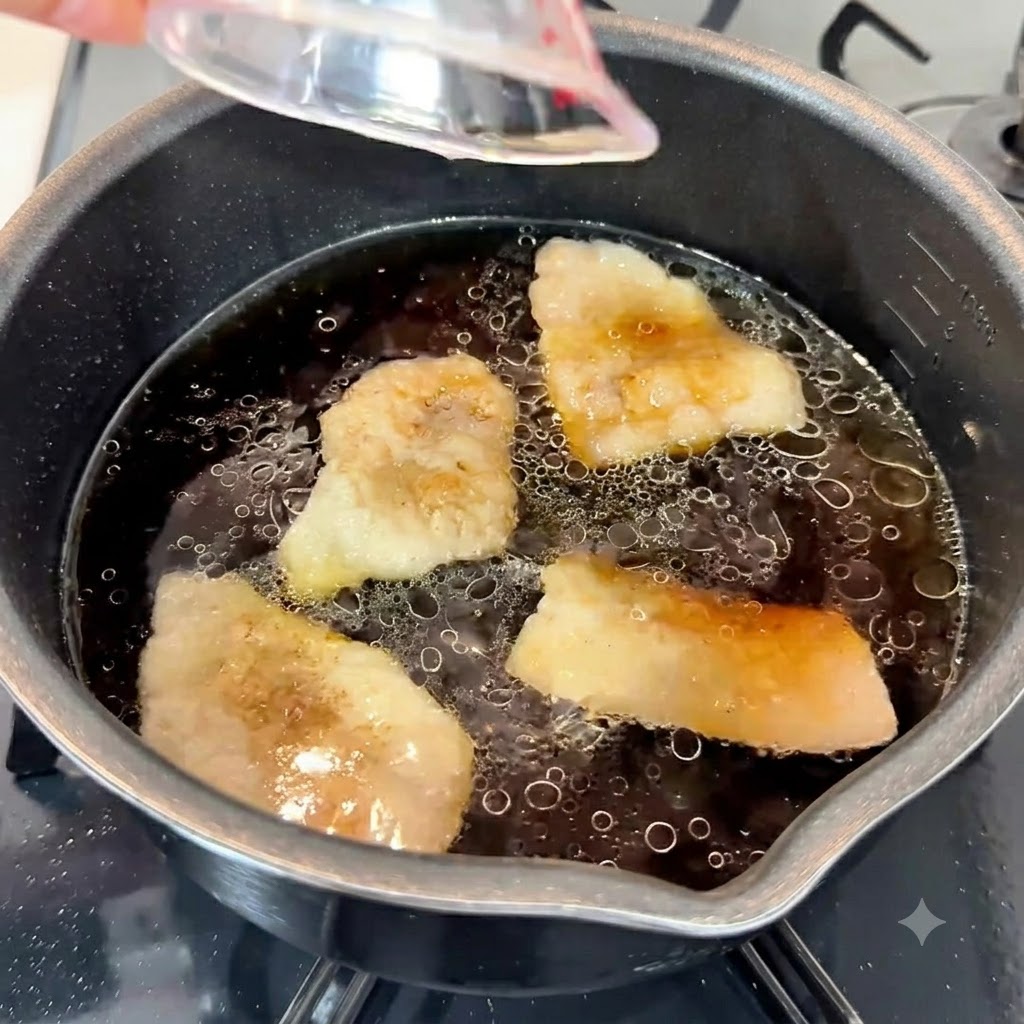 Pasta czosnkowa, olej sezamowy i biały cukier wlewane do ciemnej, aromatycznej bazy zupy w garnku.