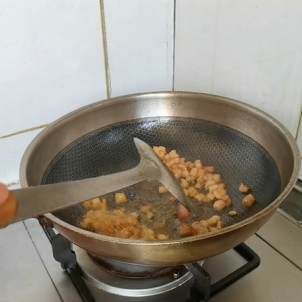 Kawałki boczku smażone w woku razem z posiekaną zieloną cebulką i czosnkiem.