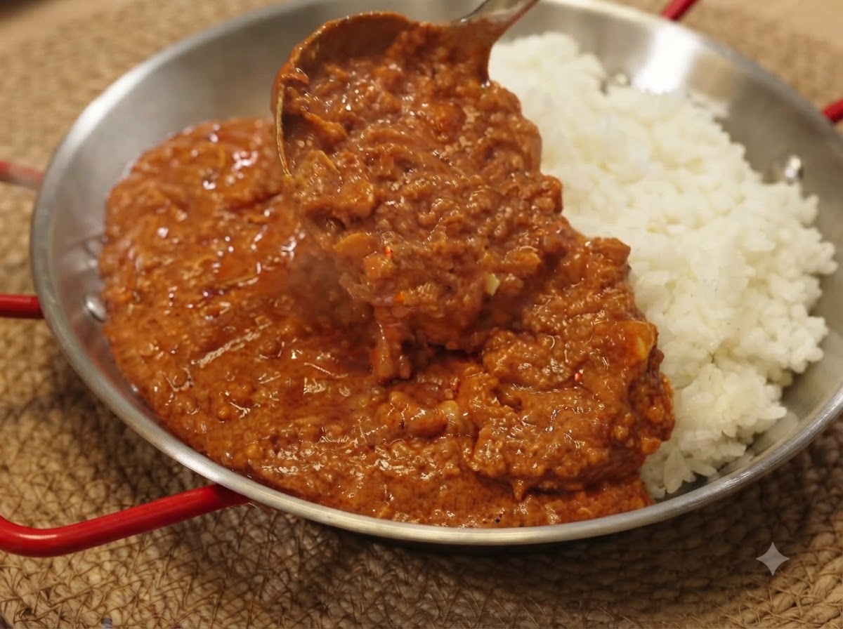 Chochelka nakładająca bogaty sos curry z mieloną wieprzowiną na porcję białego ryżu na patelni do serwowania.