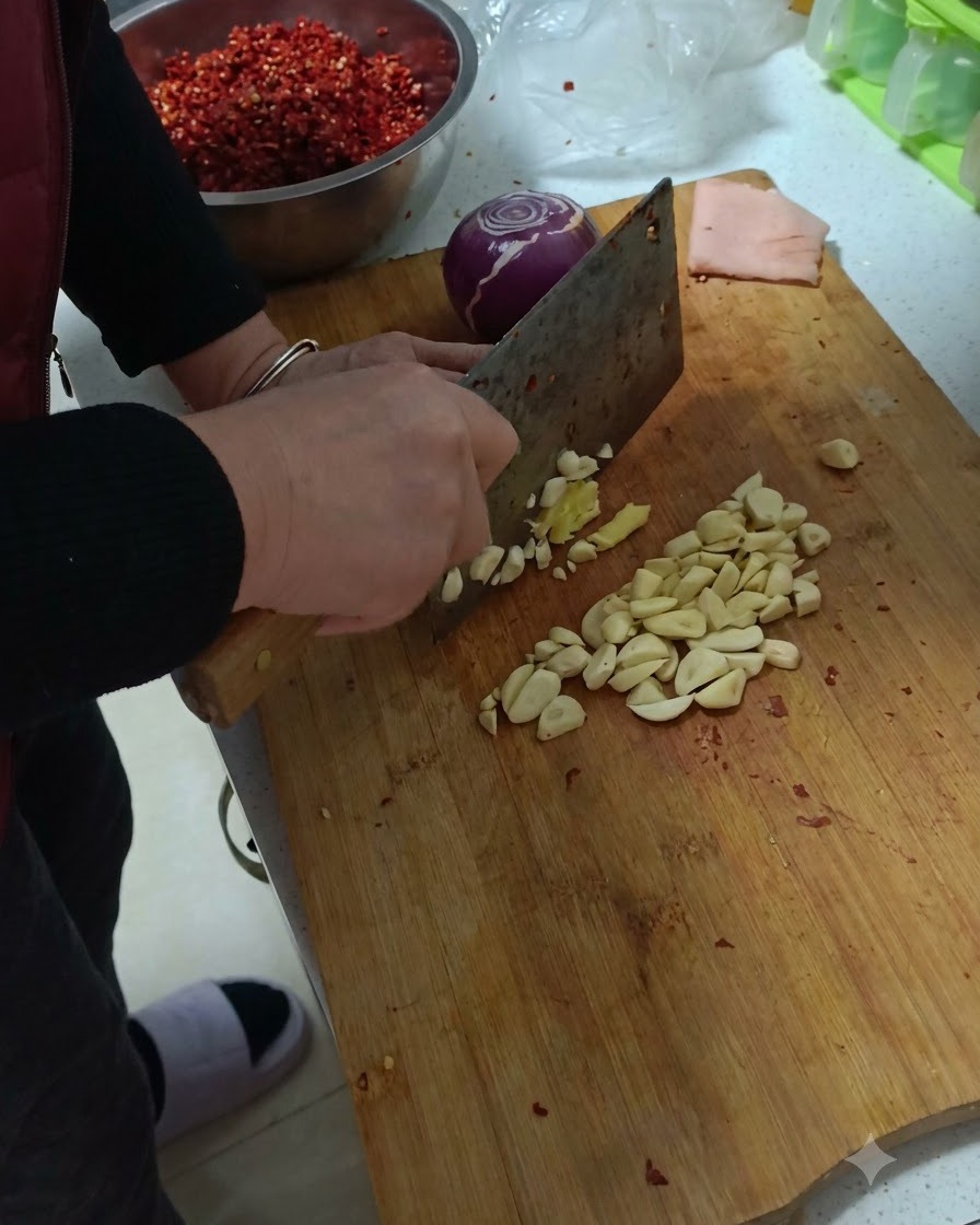 Czosnek, imbir i czerwona cebula siekane na drewnianej desce do krojenia.