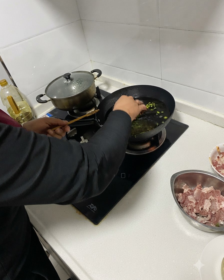Posiekane składniki dodawane do gorącego oleju w woku za pomocą pałeczek.