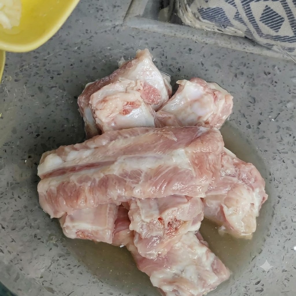 Miska z surowymi żeberkami wieprzowymi z dodatkiem świeżo posiekanego czosnku na wierzchu.