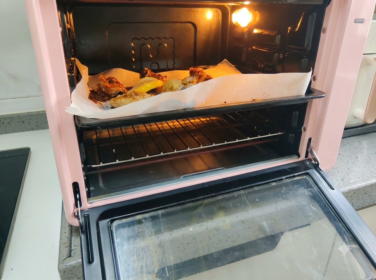 Świeże plasterki cytryny ułożone na blasze do pieczenia obok piekących się żeberek wieprzowych.
