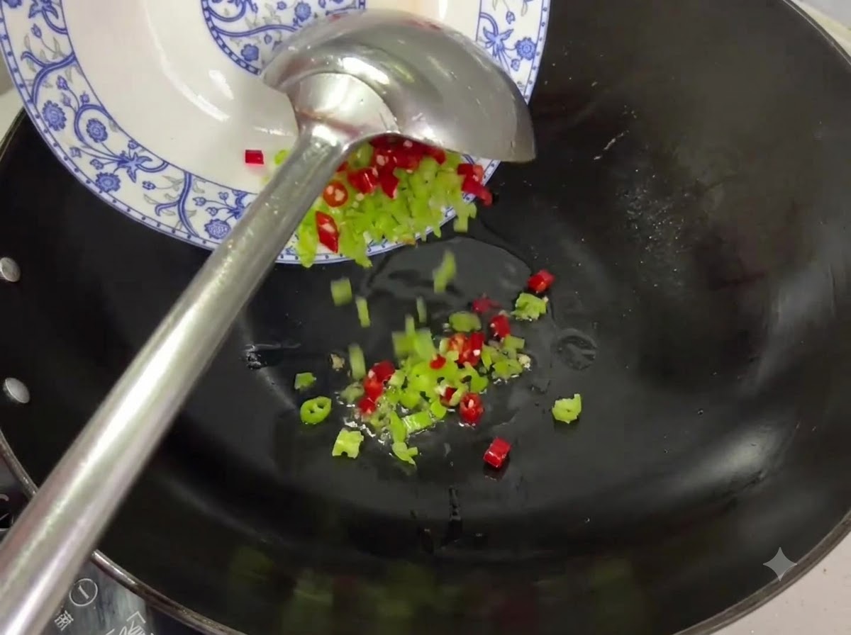 Kawałki czerwonego i zielonego chili zsypywane z talerza do woka z olejem.